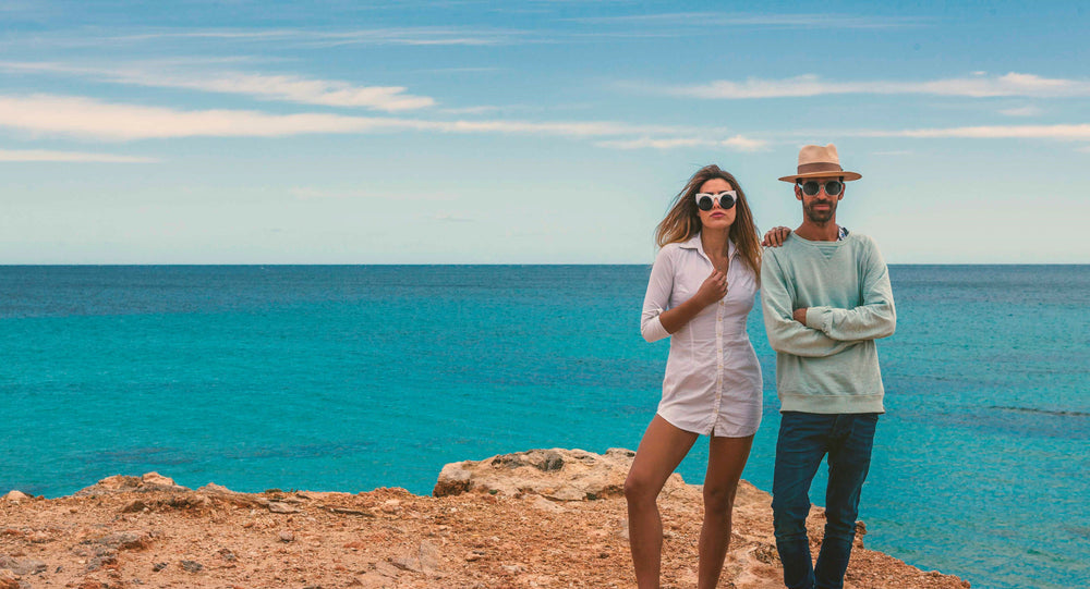 a couple stand on the beach wearing SOLFUL the best sunglasses to buy in Ibiza