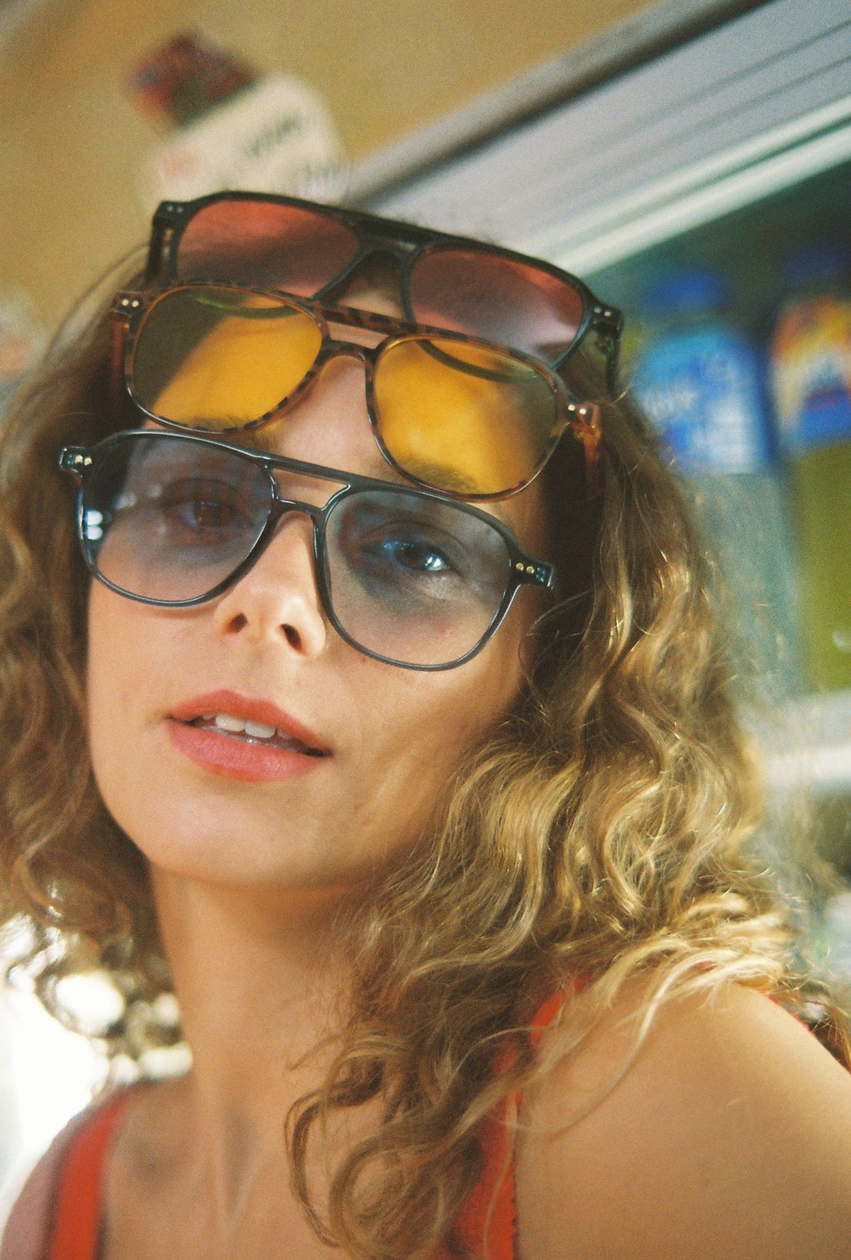 Close-up of a woman wearing three pairs of sunglasses stacked on her face